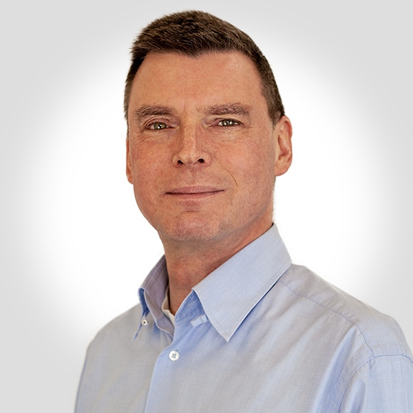 Gremler-Technischer-Leiter Der technische Leiter hat kurze dunkle Haare und trägt ein weiß-schwarz kariertes Hemd.